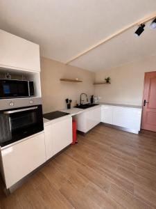 a kitchen with white cabinets and a wooden floor at Villa R-A in Kourou