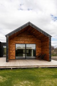 a wooden cabin with a large window on a deck at Modern Cabin with Hot Tub & Mountain views in Varmaland