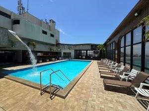 a swimming pool with chairs and a fountain on a building at Flats beira mar - praia da costa in Vila Velha