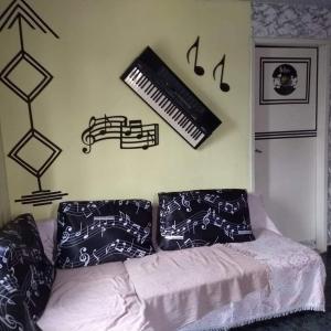 a living room with a couch and a keyboard on the wall at MZ Hostel in Campo Grande