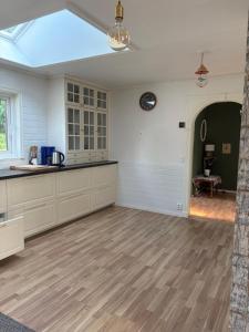 a kitchen with white cabinets and a hard wood floor at Omran House in Ystad