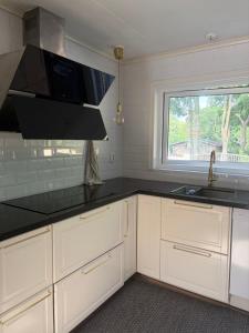 a kitchen with white cabinets and a sink and a window at Omran House in Ystad