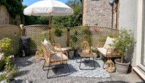 a patio with chairs and an umbrella and a table at Breach Lodge in Bonvilston