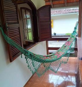 a hammock hanging in a room with windows at Palmeira Azul in Visconde De Maua