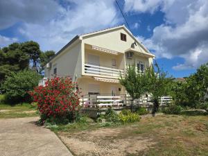 a white house with red flowers in front of it at Apartment Nella in Molat