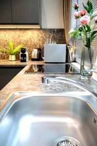 a kitchen counter with a sink and a vase of flowers at Apartman Deluxe Astrova B in Bratislava