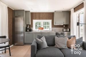 a living room with a gray couch in a kitchen at Bluebirch Cabin in Tällberg