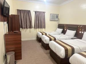 a hotel room with three beds and a television at Johraat Taba Tourist Hostel in Medina