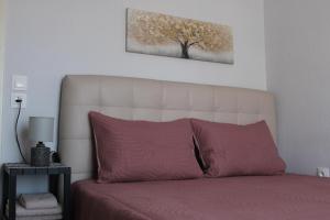 a bed with a white headboard and a tree picture on the wall at Heleni's Apartment in Aridaia