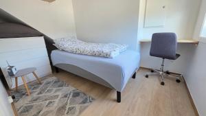 a small bedroom with a bed and a chair at Gjestehus i Tveit in Kristiansand