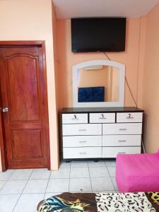 a room with a dresser with a tv and a door at Alojamientos La Escapadita in Manta