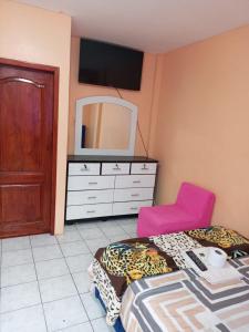 a bedroom with a bed and a dresser with a tv at Alojamientos La Escapadita in Manta