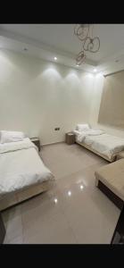 a white room with two beds and a chandelier at شقه فندقه in Hail +4 photos