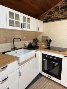 a kitchen with white cabinets and a sink at Casa D Matilde in Góis +2 photos