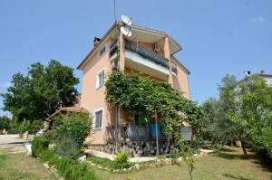 a large pink house with a balcony and trees at Apartment Akaju in Rovinjsko Selo