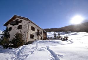 a building in the snow with the sun behind it at La Dormeuse in Livigno