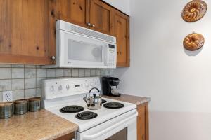 a kitchen with a white stove and a microwave at Trailside Escape a Ski-In Ski-Out Studio in SilverStar in Vernon