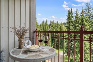 a table on a balcony with two glasses of wine at Trailside Escape a Ski-In Ski-Out Studio in SilverStar in Vernon