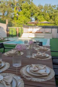 a wooden table with plates and wine glasses and flowers at Villa Bella in Čitluk