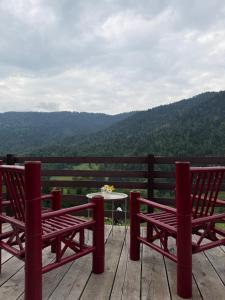 two red benches sitting on a deck with a table at Mitarbi Silence - cozy holiday cottages in mountains 