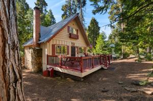 a small house with a large deck in the woods at Smoke Tree Hollow AC Pine Air in Shaver Lake
