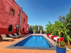 a swimming pool next to a red building at Riad Belgika Marrakech in Ourika
