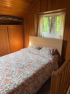 a bedroom with a bed with a floral comforter and a window at Le Petit Fournil d'Aywaille in Aywaille