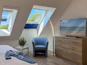 a bedroom with a tv on a dresser and a chair at Tordalk 09 in Prerow