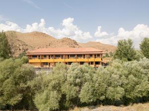 a large yellow building with mountains in the background at Lchak Hotel in Yeghegnadzor