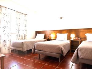 a hotel room with two beds and a table at Retiro dos Batudes in Palmela