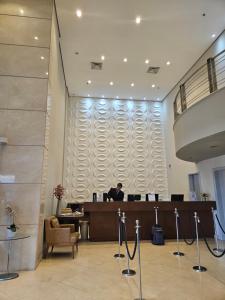 a man sitting at a desk in a lobby at Guarulhos Flat Hotel in Guarulhos