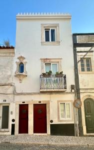 a white building with red doors and a balcony at Habita SerpaPinto in Estremoz