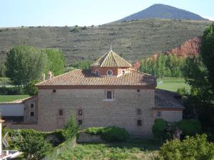 een oud gebouw met een tegeldak op een heuvel bij Apartamentos los Aljezares in Gea de Albarracín