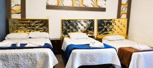 a room with three beds with white and blue sheets at Concubinas del Inca in Cajamarca