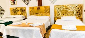 a room with three beds with white and golditures at Concubinas del Inca in Cajamarca
