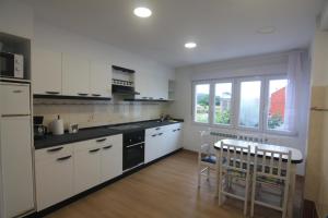 a kitchen with white cabinets and a table and chairs at Fogar dos Americanos in Borneiro
