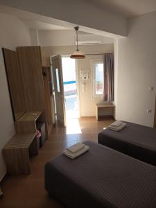 a room with two beds and a door to the ocean at Syrtaki Studios in Kámpos