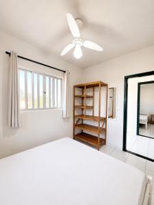 a white bedroom with a bed and a ceiling fan at Solar das Andorinhas Pousada in Itapoa