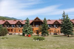 a large log house with trees in front of it at Glacier House Hotel & Resort in Revelstoke