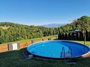 a swimming pool in the middle of a grass field at Domek DeLuxe Spa z sauną i jacuzzi- Nowy Targ blisko Zakopanego i Białki Tatrzańskiej in Nowy Targ