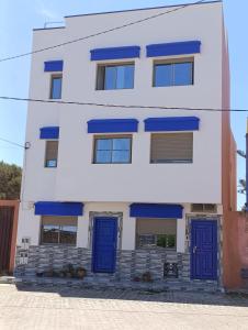 a white and blue building with blue doors at Appartements Hajar in Oualidia