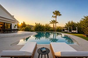 a swimming pool with two lounge chairs and a table at Gregorys Private Luxury Villa with Heated Pool & Gardens in SFakianalíon