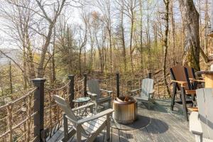 a deck with chairs and a grill and trees at Breathtaking Boutique Treehouse nestled in clouds in Beech Mountain