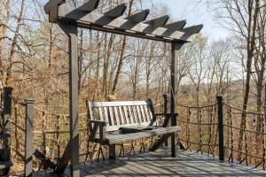 a wooden bench sitting on top of a wooden deck at Breathtaking Boutique Treehouse nestled in clouds in Beech Mountain