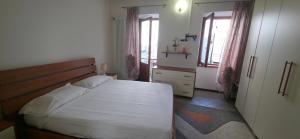 a bedroom with a large white bed and two windows at Deby House in Oggebbio