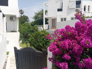 a gate with pink flowers in front of a white building at Maison de plage familiale à Cabo in Cabo Negro