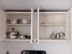a kitchen with white cabinets with pots and pans at Maison de plage familiale à Cabo in Cabo Negro