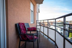 two chairs on a balcony with a view of a city at VukaNest apartman Jagodina in Jagodina
