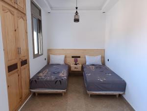 a bedroom with two beds and a nightstand and sidx sidx sidx sidx at Appartements Hajar in Oualidia