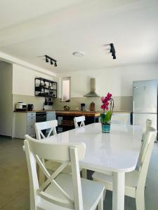 a white dining room table with white chairs and a kitchen at Porto Vista Apartments Kumbor in Kumbor